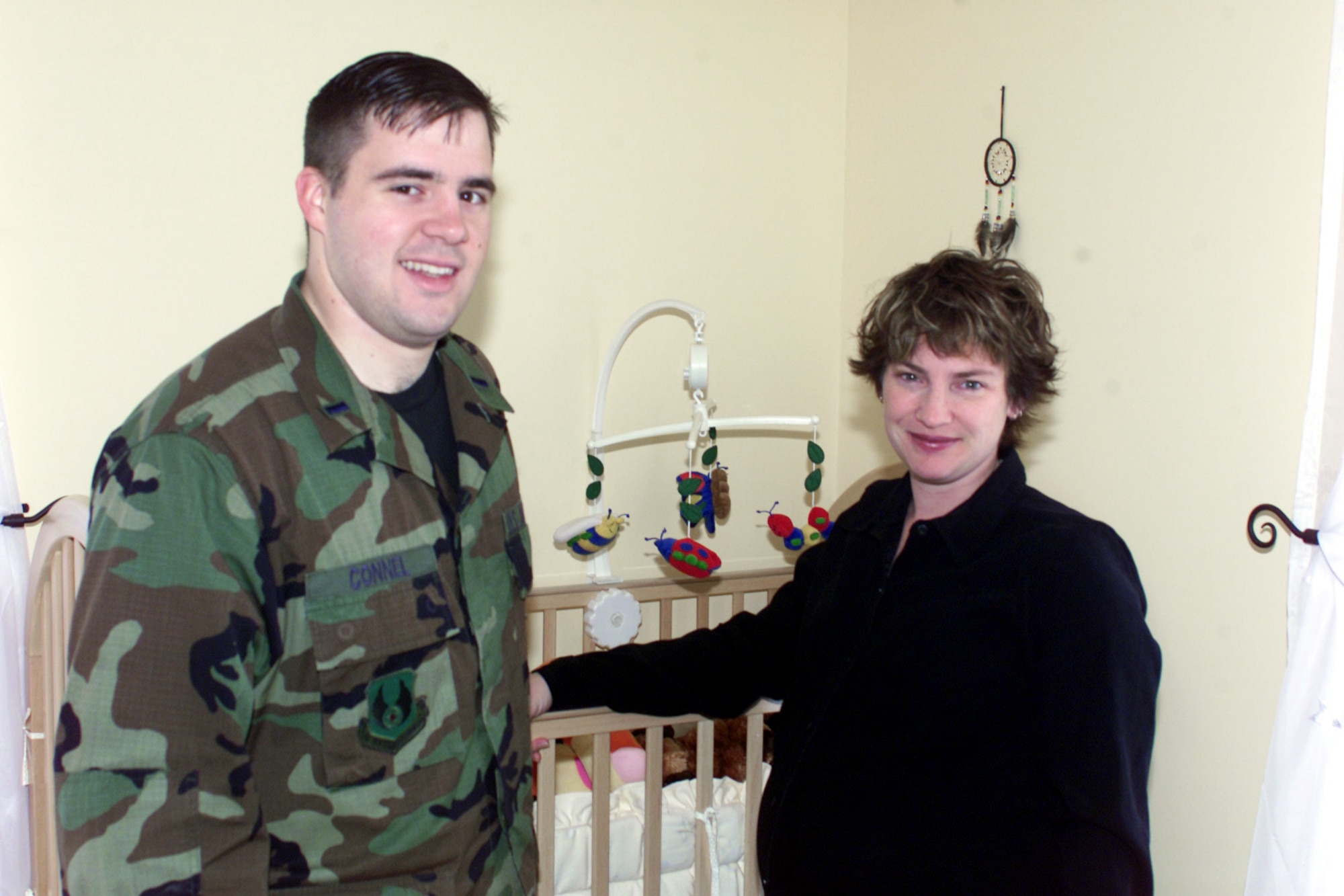 HANSCOM AIR FORCE BASE, Mass. -- Jenn Connel (right) had her husband, 1st Lt. Brandon Connel, pose in their home nursery before their son, Grayson Riley, was born Dec. 22.  Mrs. Connel is a breast cancer survivor who did not give up her dream of breastfeeding her son even though she had a double mastectomy.  (U.S. Air Force photo by Tech. Sgt. Eric M. Grill)
