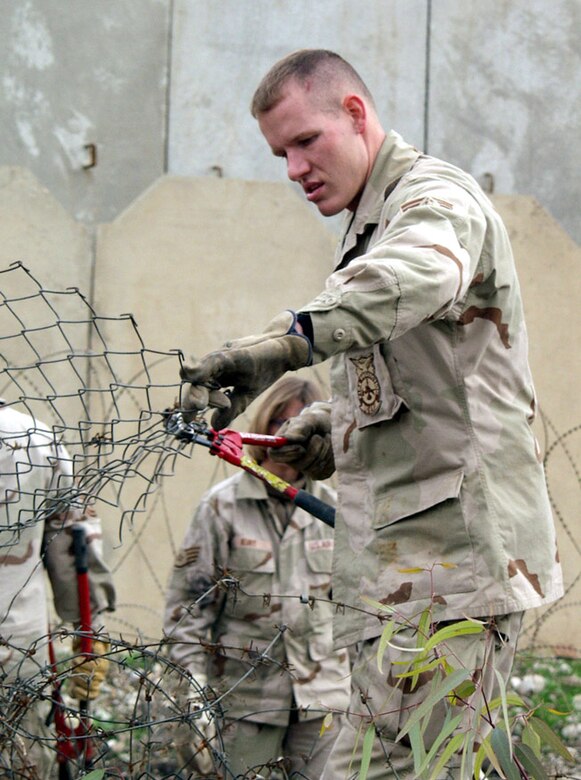 KIRKUK AIR BASE, Iraq -- Staff Sgt. Ryan Darnell cuts through a damaged chain-link fence during the Jan. 11 cleanup effort to help restore a mosque here.  Sergeant Darnell is assigned to the 506th Expeditionary Civil Engineer Squadron here.  (U.S. Air Force photo by Tech. Sgt. Jeffrey Williams)