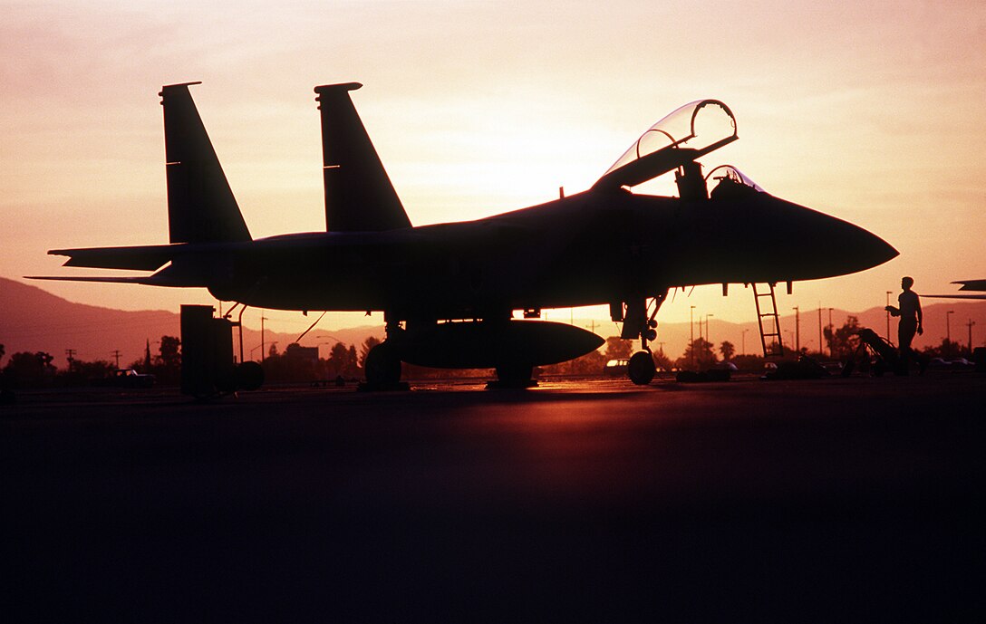 1990's -- An F-15C Eagle aircraft of the 1st Tactical Fighter Wing is silhouetted against the sunrise while on a combat patrol near the Iraqi border during Operation Desert Shield.  