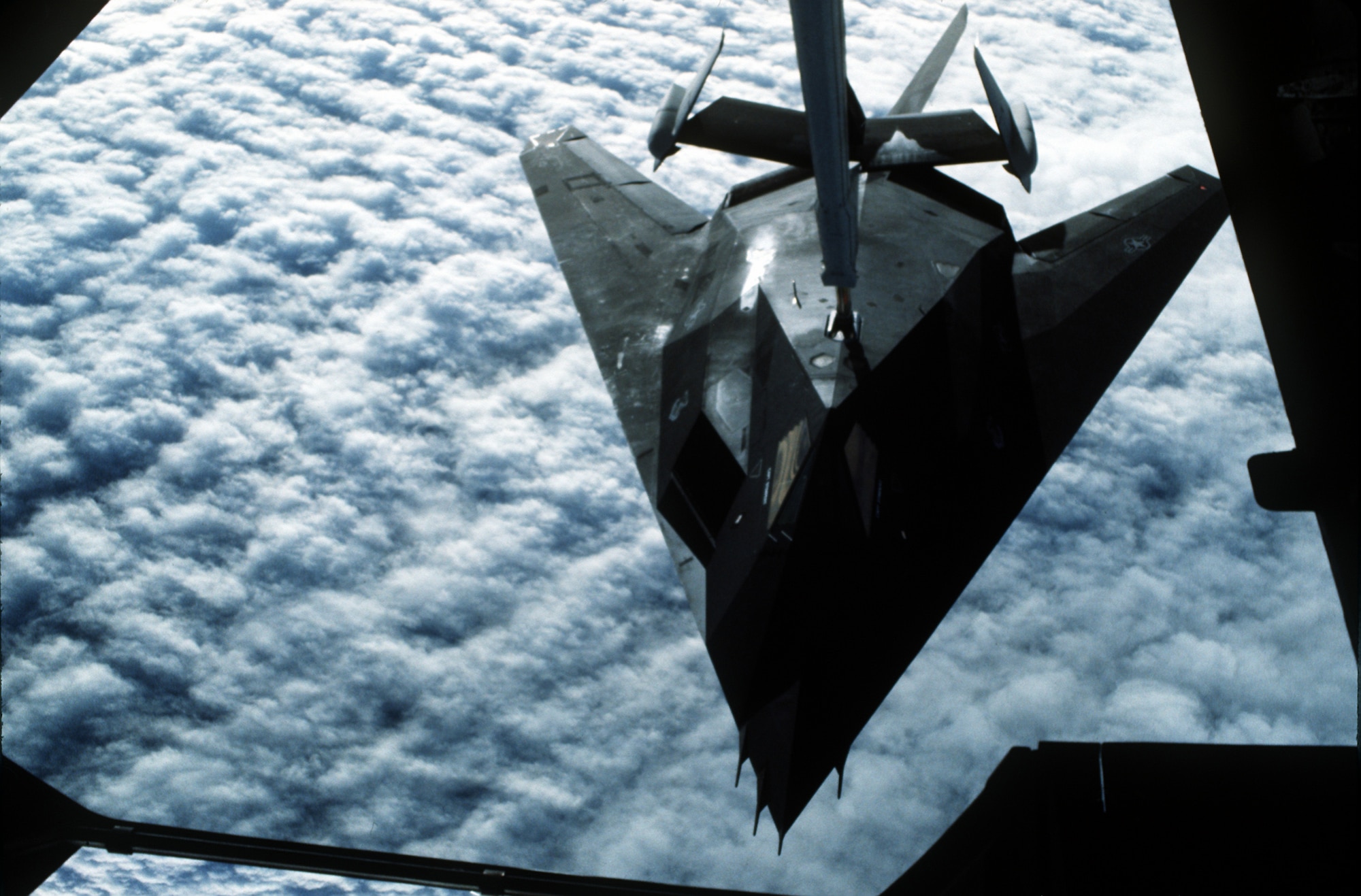 1990's -- A 37th Tactical Fighter Wing F-117A stealth fighter aircraft refuels from a 22nd Air Refueling Wing KC-10 Extender aircraft during Operation Desert Shield.  The F-117A is en route to Saudi Arabia.  