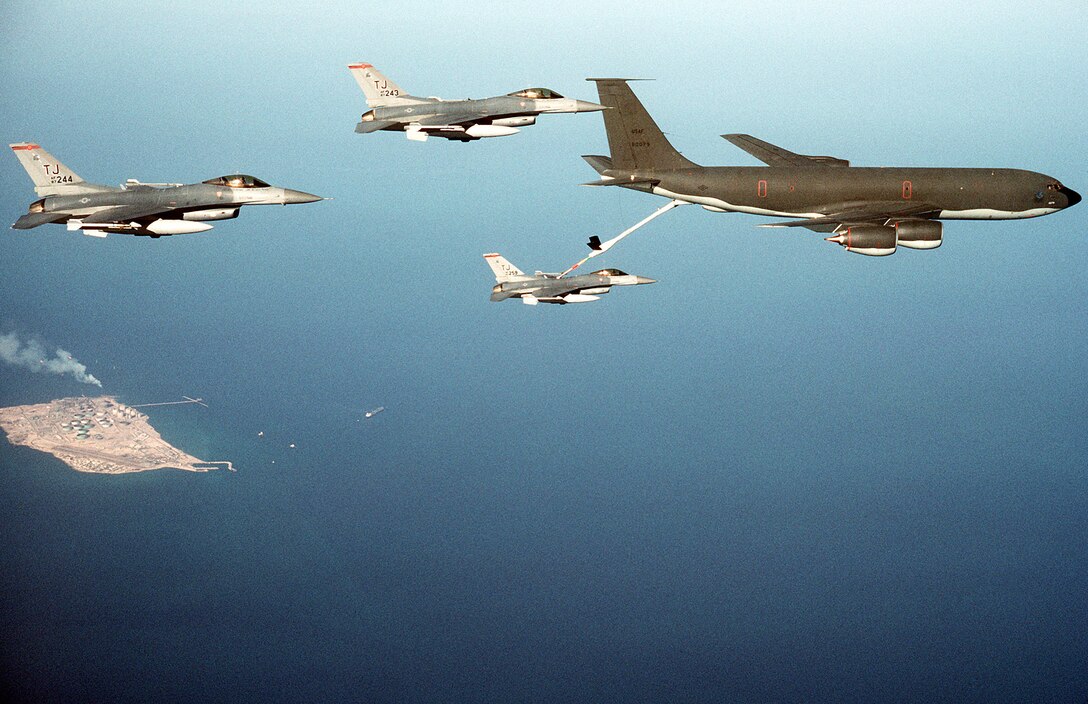 1990's -- A KC-135R Stratotanker refuels an F-16C Fighting Falcon fighter aircraft from the 614th Tactical Fighter Squadron (TFS), 401st Tactical Fighter Wing of Torrejon Air Base, Spain, as two other Fighting Falcons from the 614th TFS fly alongside during Operation Desert Shield.  