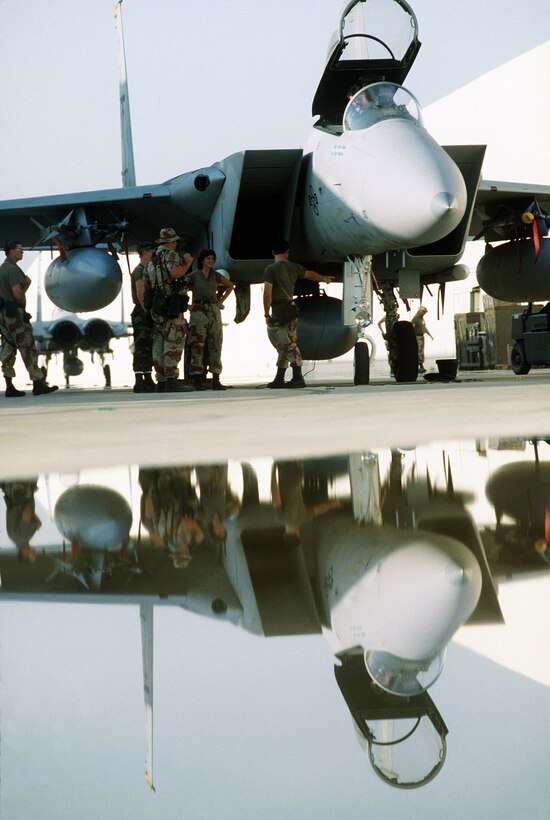 1990's -- A combat photographer and ground crew members stand beside a 1st Tactical Fighter Wing F-15C Eagle aircraft, armed with AIM-9 Sidewinder and AIM-7 Sparrow missiles, during Operation Desert Shield.  
