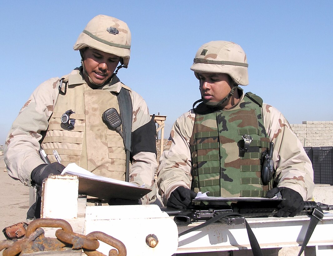 KIRKUK AIR BASE, Iraq -- Senior Airman Justin Yazza (left) goes over the priority access list here with Army Cpl. David Concepcion.  The list tells escorts which laborers to grant priority access to on any given day.  Airman Yazza is assigned to the 506th Air Expeditionary Group's escort flight and is deployed from Barksdale Air Force Base, La.  (U.S. Air Force photo by Senior Master Sgt. Gene LaDoucer)