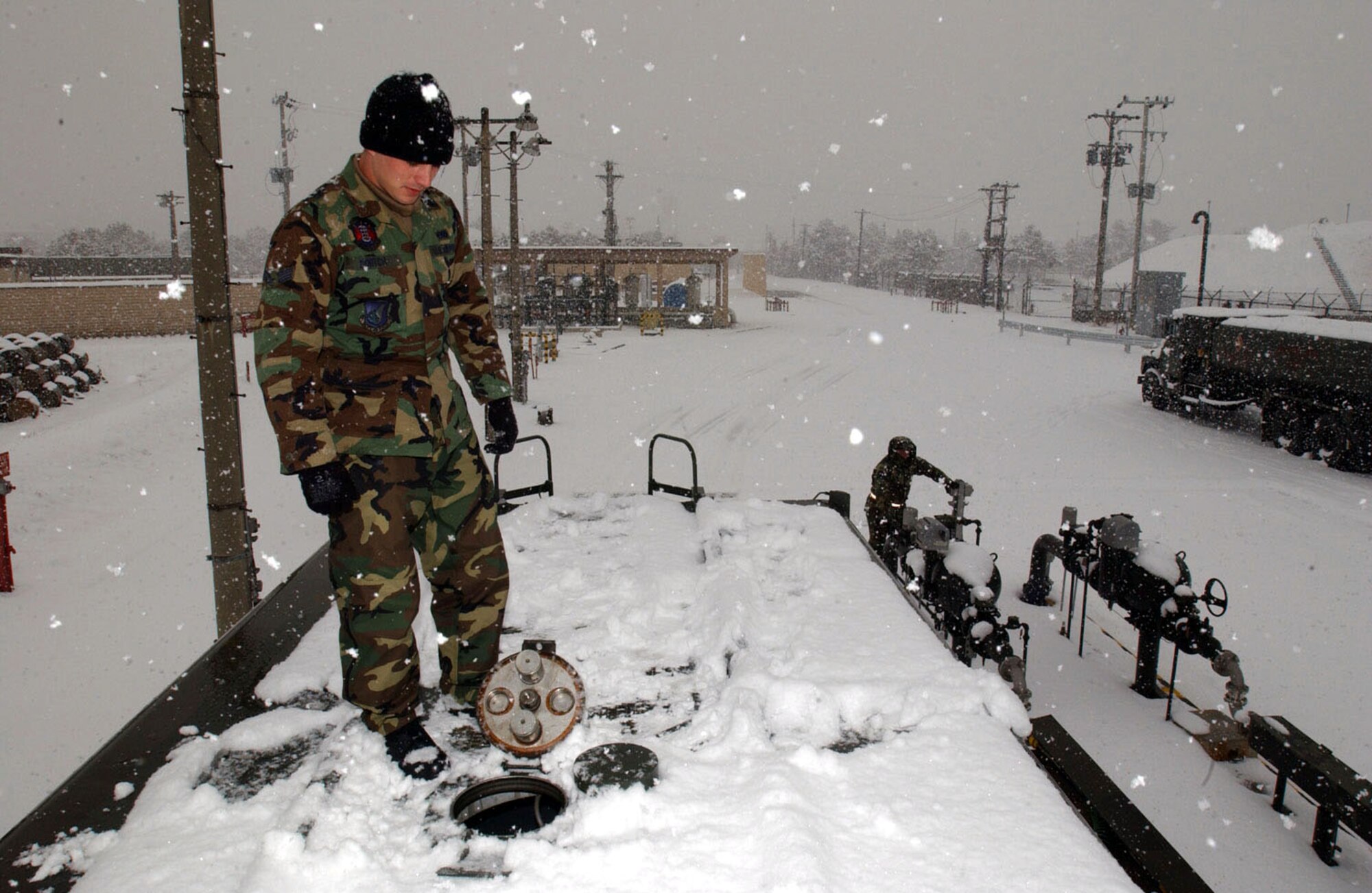KWANG JU AIR BASE, South Korea -- As the snow falls, Airman 1st Class Blake Dortch checks the fuel level while co-worker, Staff Sgt. Michael Nelson, stands ready at the fuel shutoff switch.  Both airmen from Kadena Air Base, Japan, participated in a four-day deployment here.  They are assigned to the 18th Logistical Readiness Squadron.  (U.S. Air Force photo by Tech. Sgt. Richard Freeland)