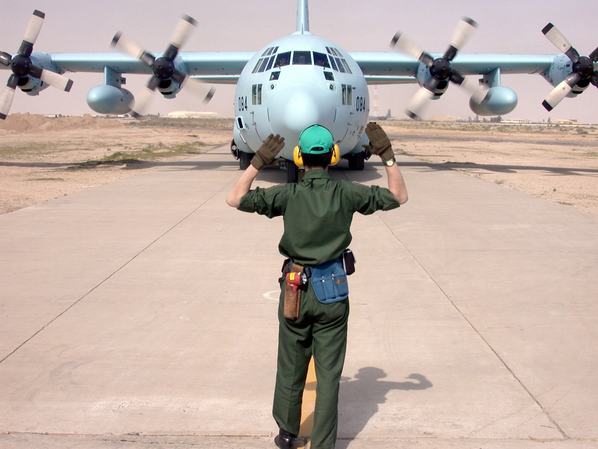 SOUTHWEST ASIA -- A technician with the Japanese air self-defense forces marshals in the first of three C-130Hs to arrive at a forward-deployed location Jan. 30.  The Japanese have not deployed to a hostile location since World War II.  They will be working closely with coalition forces to promote humanitarian missions.  (U.S. Air Force photo by Senior Airman James C. Dillard)
