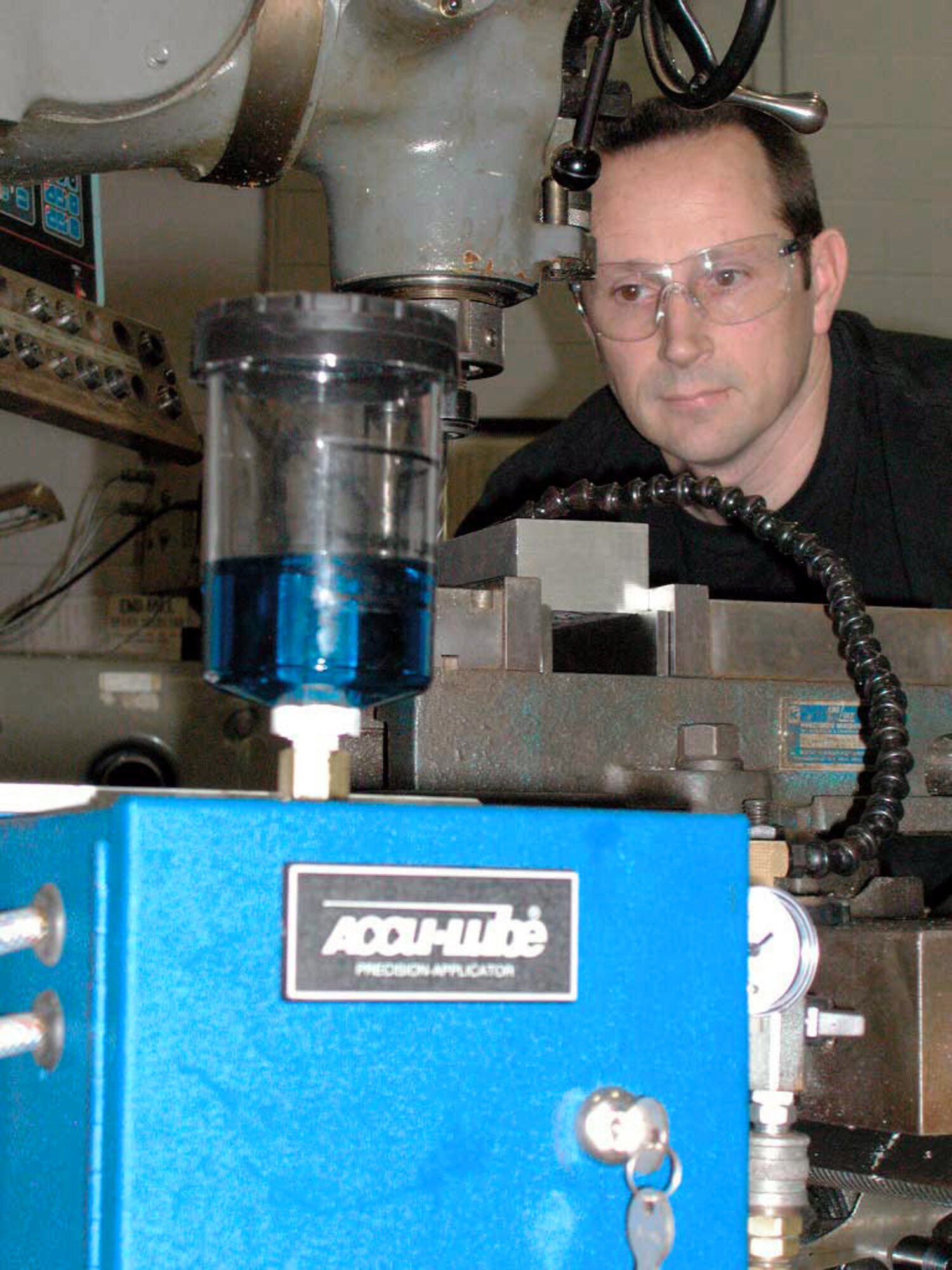 WRIGHT-PATTERSON AIR FORCE BASE, Ohio -- Staff Sgt. Nathan Moffitt drills through a 3-inch by 5-inch aluminum block using an Accu-Lube unit.  The environmentally friendly Accu-Lube uses soybean-based biodegradable oil and compressed air to lubricate metal components that are being machined or drilled.  Sergeant Moffitt is assigned to the 445th Maintenance Squadron's machine shop here.  (U.S. Air Force photo by Staff Sgt. Charles Miller)