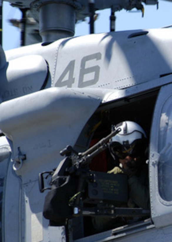 Navy Petty Officer 3rd Class Nick Tookenay mans the gun mount on a MH-60S Knighthawk helicopter as it takes off from deck of the amphibious assault ship USS Kearsarge (LHD 3) on June 20, 2004. The Kearsarge is transporting elements of the 24th Marine Expeditionary Unit in support of Operation Iraqi Freedom. 