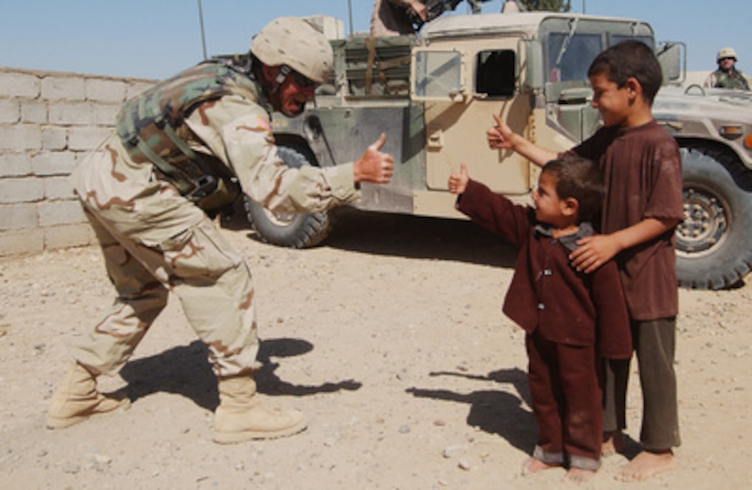 Army Spc. Tim Brunson gives the thumbs up to some Iraqi children during a Medical Civil Assistance Program on June 22, 2004. Brunson is a tank driver from the 1-185th Armor Division. 