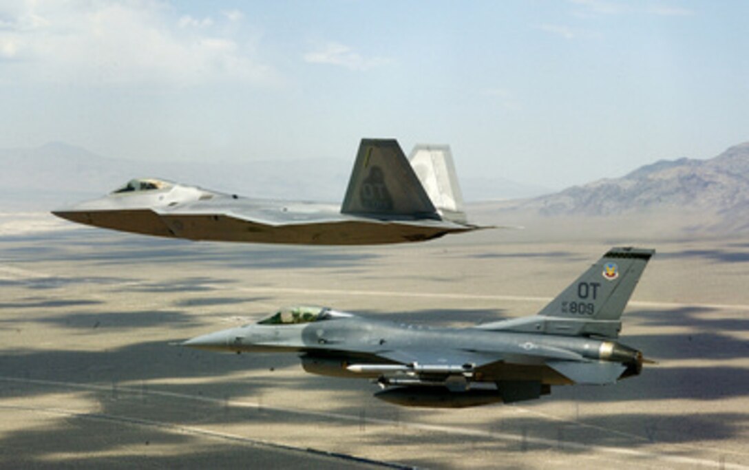 A U.S. Air Force F/A-22 Raptor and an F-16 Fighting Falcon fly in a fingertip formation on a training mission from Nellis Air Force Base, Nev., on June 23, 2004. The F/A-22 is piloted by Maj. David Thole, 422nd Test and Evaluation Group and the F-16, is piloted by Maj. Alex Grynkewich, 53rd Test and Evaluation Group. Both Thole and Grynkewich are from Nellis Air Force Base, Nev. 