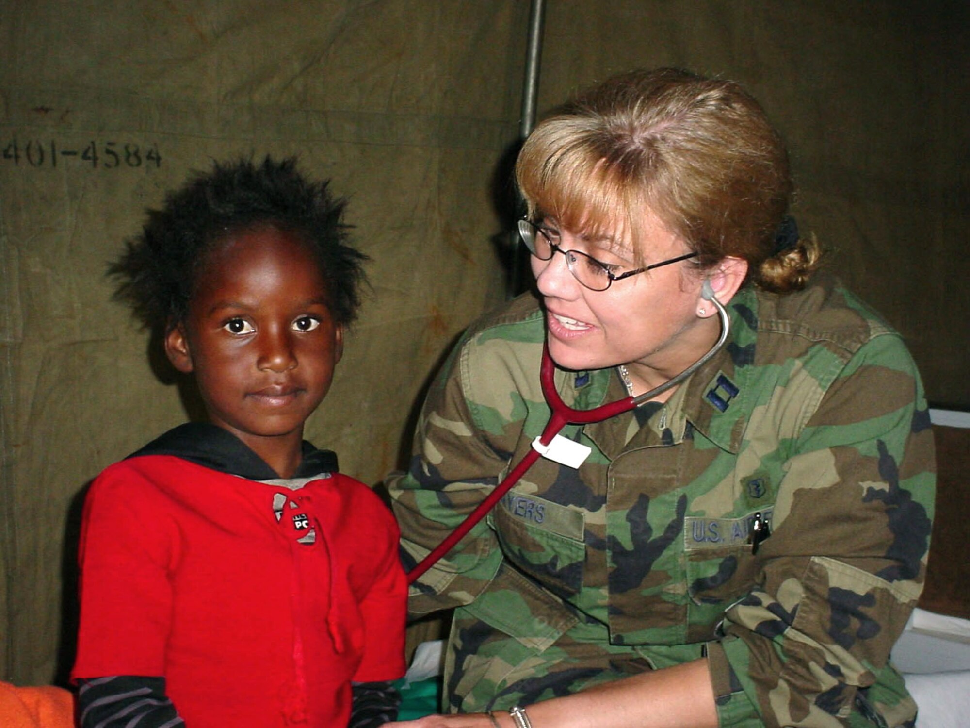DITHOLO, South Africa -- Capt. Karyn Ayers, a family practitioner, listens to a child's breathing patterns to determine what kind of medical treatment she needs.  Captain Ayers is part of a team of medics from the 48th Medical Group at Royal Air Force Lakenheath, England, who saw more than 600 patients here on their first day of MedFlag 2004.  The annual two-week joint-combined medical training and civil assistance exercise provides rare medical training for U.S. Air Force medics and their South African defense force counterparts.  (U.S. Air Force photo by Master Sgt. Doris Libby)