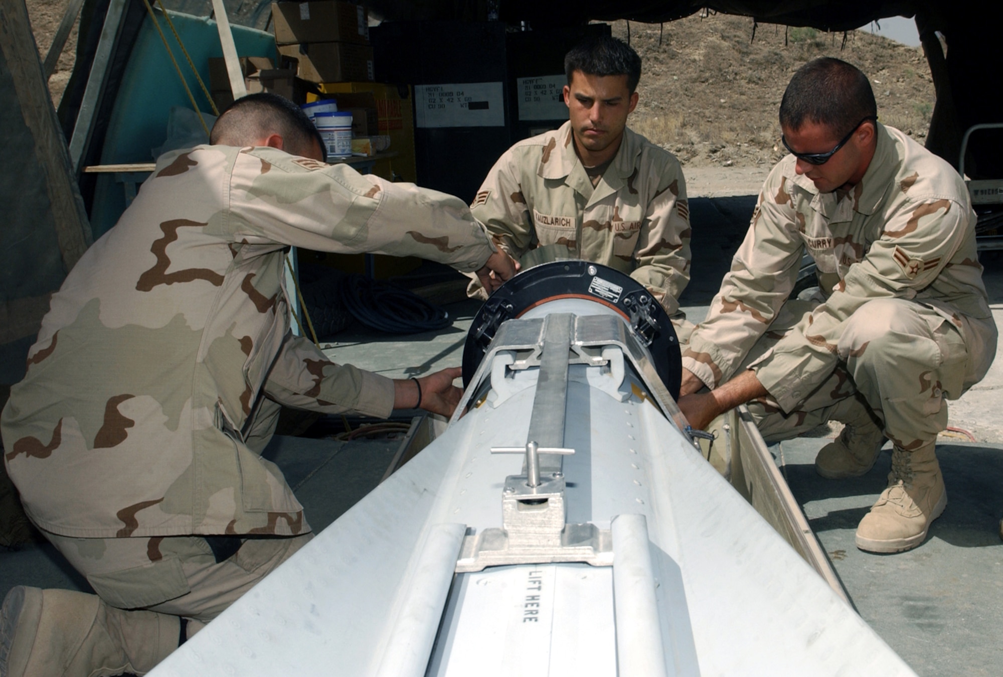 BAGRAM AIR BASE, Afghanistan -- (From left) Senior Airmen Luis DeLeon, Kenneth Kauzlaurich and Airman 1st Class Brett Curry attach a testing unit to the guidance system on a Maverick missile.  The testing unit verifies the Maverick can identify and steer to a target.  The Airmen are assigned to the 455th Expeditionary Aircraft Maintenance Squadron and are deployed from Eielson Air Force Base, Alaska.  (U.S. Air Force photo by Master Sgt. Andrew Gates)
