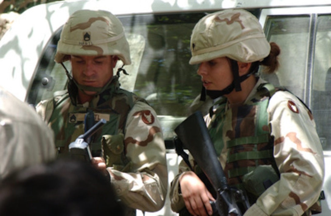 Army Staff Sgt. Hartl (left) and Spc. Hatch check communications during a groundbreaking ceremony for the Mohammad Mullah Shaheed Secondary School in the Parwan Province of Afghanistan, on June 29, 2004. The Parwan Provincial Reconstruction Team out of Bagram Air Field provided coordination for the construction. Hartl and Hatch are deployed with the 34th Infantry Division's, 1st Brigade, 168th Infantry Regiment. 