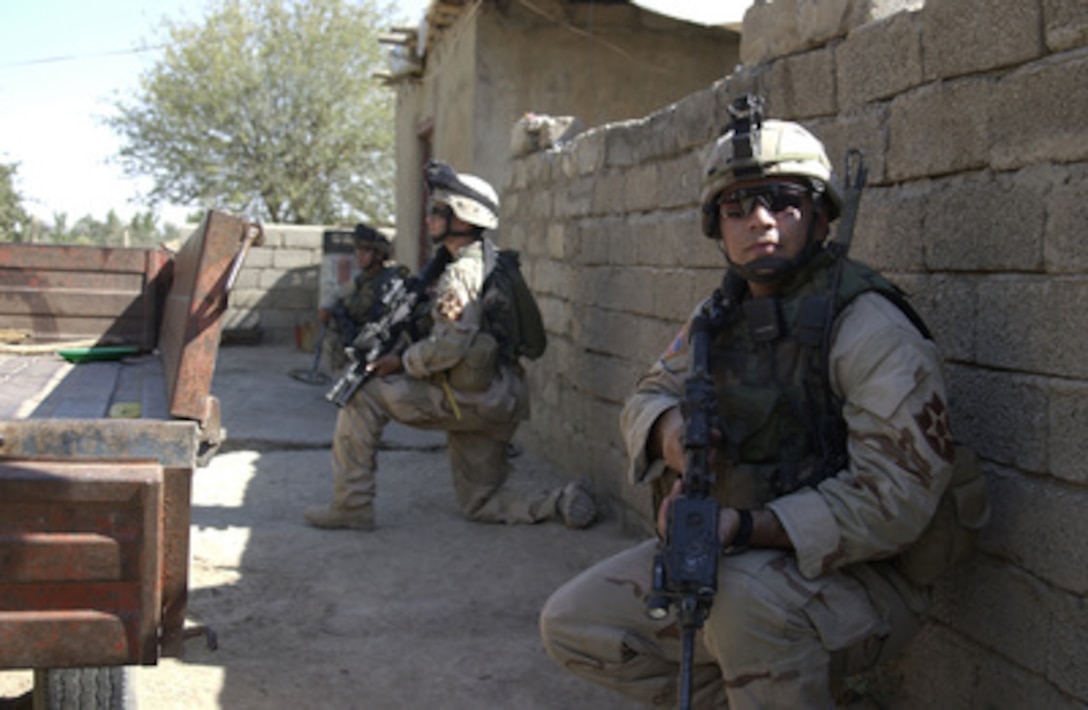 Army soldiers provide security for Iraqi National Guard soldiers as they search a house during Operation Mutual Security II in Mosul, Iraq, on July 3, 2004. The Iraqi police and the Iraqi National Guard are conducting cordon and knock operations in search of weapons caches while U.S. Army soldiers from the 3rd Infantry Regiment, 3rd Brigade, 2nd Infantry Division, Stryker Brigade Combat Team, provide blocking positions for the outer cordon. 