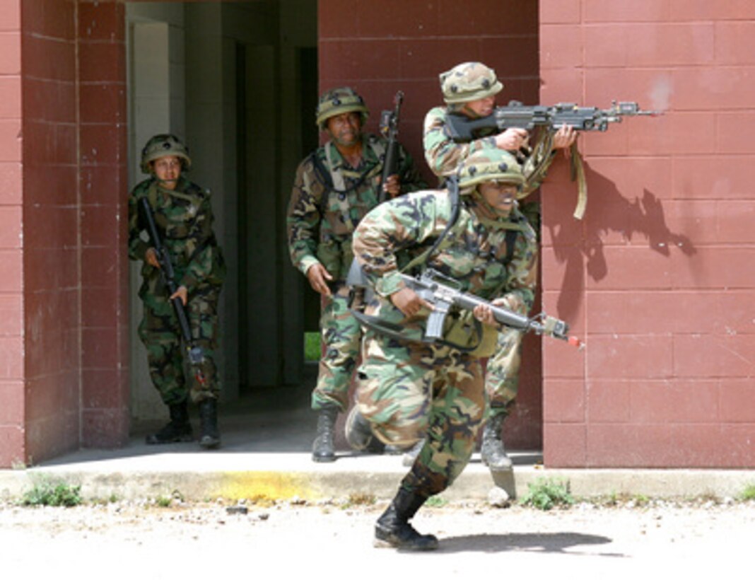 Army Spc. Victor Peterson runs across a street as Pvt. Carl Snider provides suppressive fire against a simulated sniper during Exercise Samurai Sword 2004 while Spc. Santa Rahola (left) and Staff Sgt. Donald Wyche, wait their turn to run across the street on June 27, 2004. Samurai Sword is designed to provide warrior-focused training for the 4th Theater Support Command's enlisted combat service support soldiers and is held at a Military Operation in Urban Terrain training facility on Fort Hood, Texas. 