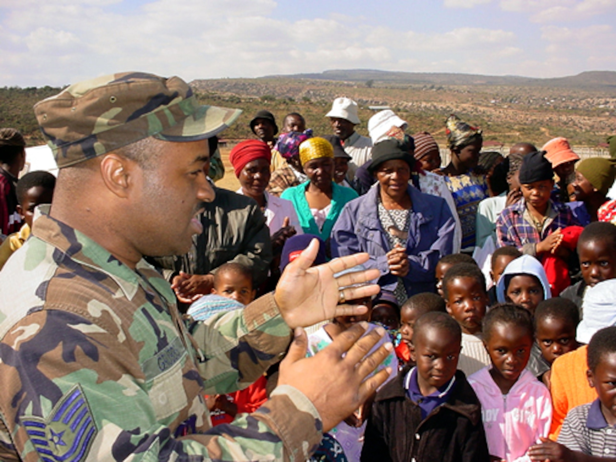 KGAUTSWANE, South Africa -- Tech. Sgt. Victor D. Grubbs leads and teaches children of the community development center here a song July 10.  Airmen, who deployed to South Africa for the MedFlag 2004, delivered donations to the children. Sergeant Grubbs is from 3rd Air Force at Royal Air Force Mildenhall, England.  (U.S. Air Force photo by Master Sgt. Doris Libby)