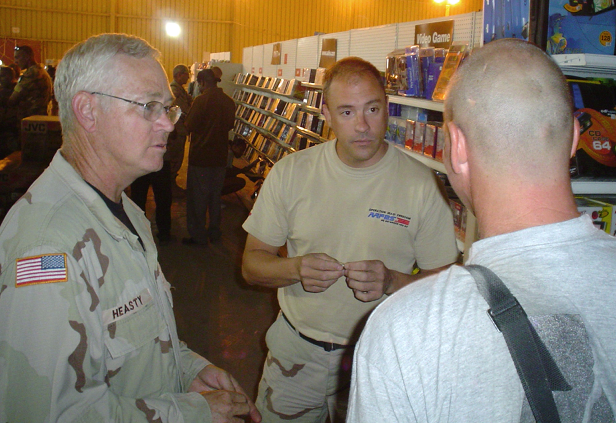 TALLIL AIR BASE, Iraq -- Allen Heasty (left) and Timothy Adams talk to a customer in the newly air-conditioned Army and Air Force Exchange Service facility here.  Mr. Heasty is the AAFES southern Iraq general manager, and Mr. Adams is the main exchange team leader.  (U.S. Air Force photo by Master Sgt. Debbie Aragon)