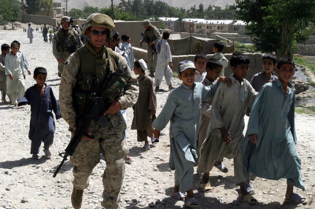 Lance Cpl. Holt from Company I, 3rd Battalion, 6th Marine Regiment, is accompanied by a group of Afghan boys as he conducts a security patrol through Surobi, Afghanistan, on May 23, 2004. The battalion is conducting security patrols and civil assistance operations throughout the region in support of Operation Enduring Freedom. 