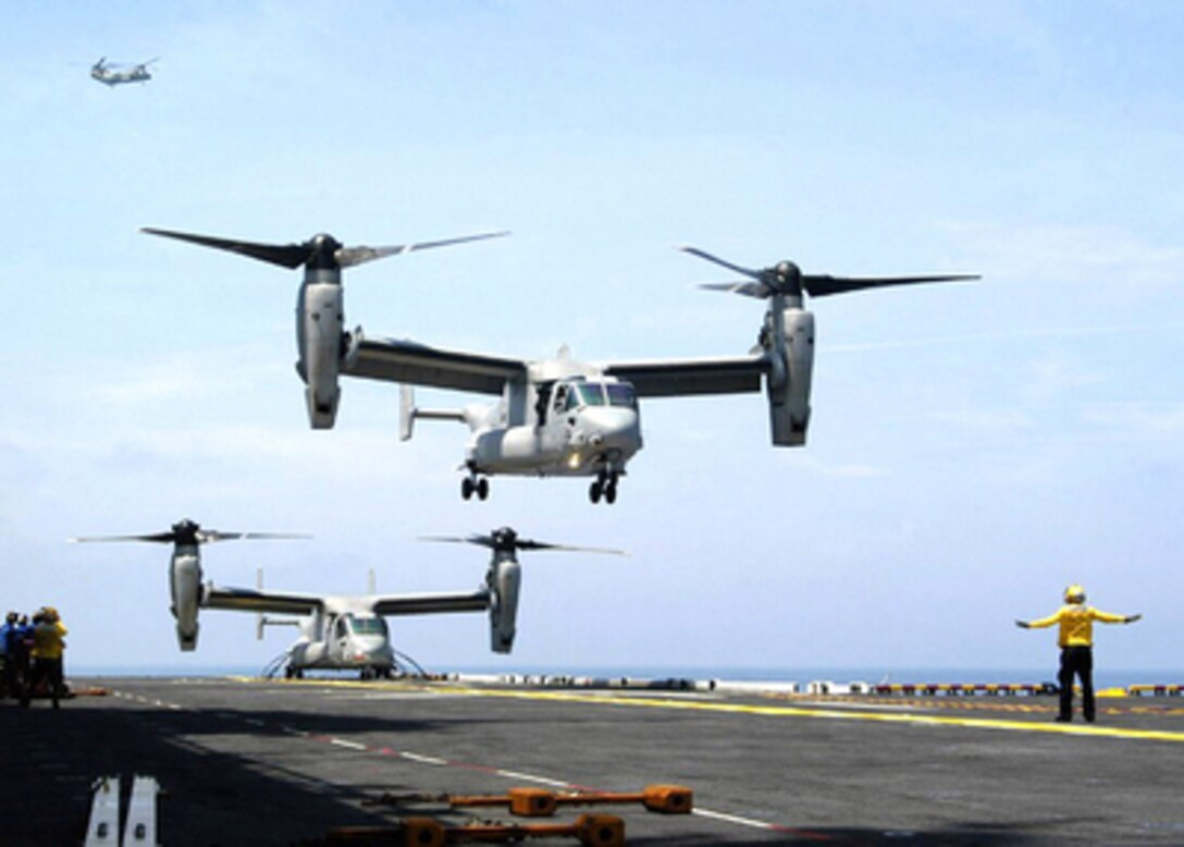 Two U.S. Navy V-22 Osprey aircraft operate from the flight deck of the USS Iwo Jima (LHD 7) during developmental testing on July 1, 2004. The Osprey is a tilt-rotor vertical/short takeoff and landing multi-mission aircraft developed to fill joint-service, global combat operational requirements. 