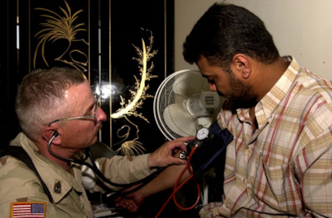 Army 1st Sgt. Lloyd Creeger of Charlie Company, 118th Medical Battalion takes a local Iraqi man's blood pressure during a Medical Civil Action Program in Khoum Abu Halan, Iraq, on July 9, 2004. 
