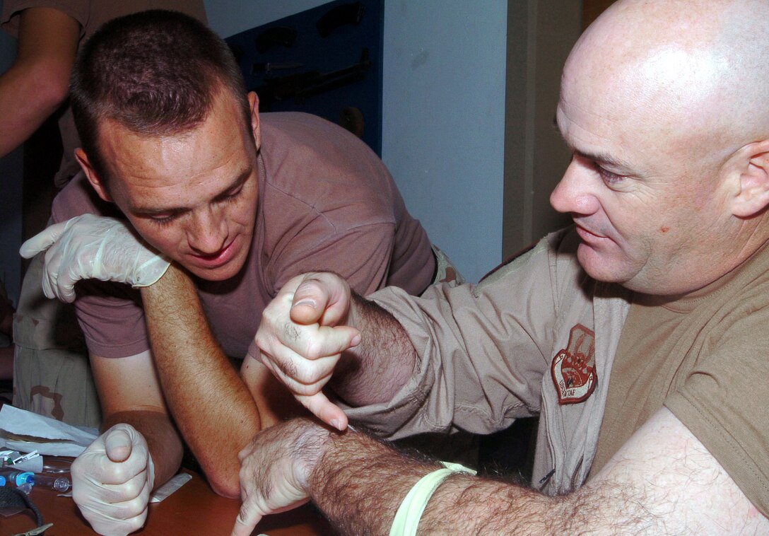 BALAD AIR BASE, Iraq -- Master Sgt. Michael Strickland (right) shows Airman 1st Class Jacob Green the best way to insert an intravenous needle.  Sergeant Strickland is assigned to the 64th Expeditionary Rescue Squadron here and is deployed from the 347th Medical Group at Moody Air Force Base, Ga.  Airman Green is assigned to the 332nd Expeditionary Security Forces Squadron here and is deployed here from the 28th Security Forces Squadron at Ellsworth AFB, S.D.  (U.S. Air Force photo by Staff Sgt. Cohen Young)