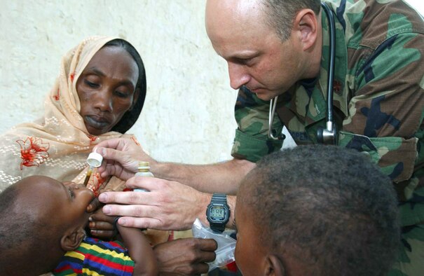 CAMP LOUMIA, Chad -- Maj. Mike Cooper gives a Chadian baby medication while on a humanitarian mission here.  He is a physician assistant with the 445th Aerospace Medical Squadron at Wright -Patterson Air Force Base, Ohio.  The medical team treated more than 2,800 patients and issued 500 pairs of donated eye glasses.  (U.S. Air Force photo by Tech. Sgt. Chance Babin)