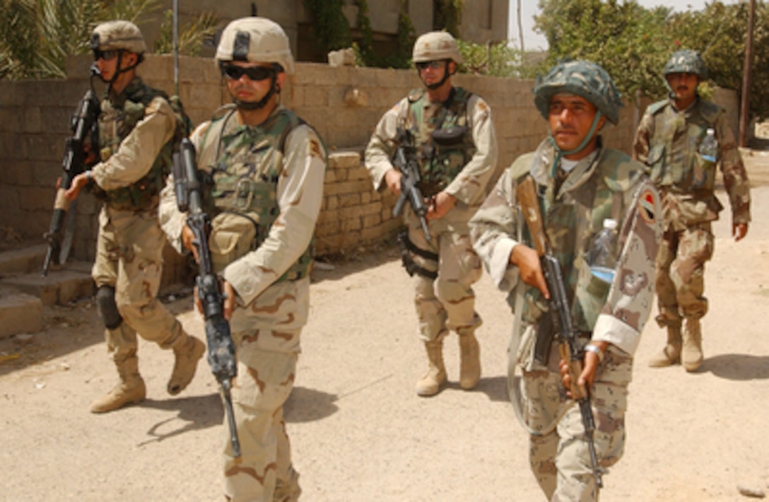 Iraqi National Guardsmen (right) patrol alongside their coalition counterparts in the village of Albu Hassan, Iraq, on July 16, 2004. Coalition troops have entered into a training and assistance role now that the Iraqi National Guard has taken the lead in security following the June 28, 2004 transfer of power in Iraq. 