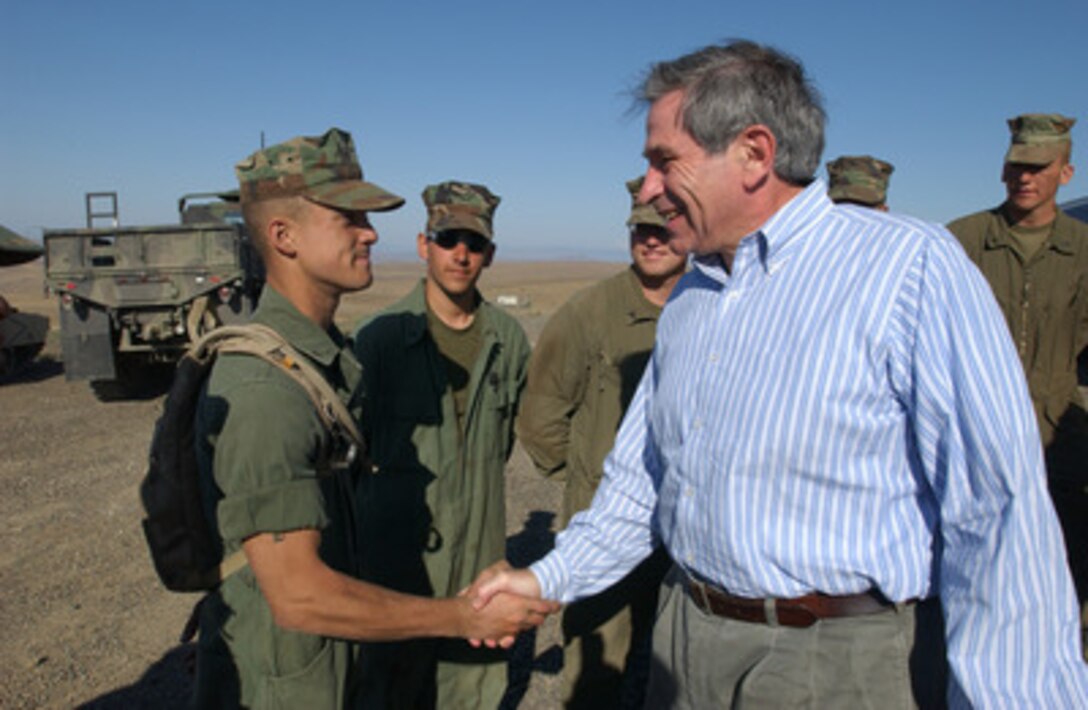 Deputy Secretary of Defense Paul Wolfowitz smiles and shakes the hand of Marine Corps Lance Corporal Robert A. James at Yakima Training Center in Yakima, Wash., on July 24, 2004. Wolfowitz traveled to Yakima to observe military exercises. James is a tank mechanic from the 4th Marine Tank Battalion. 