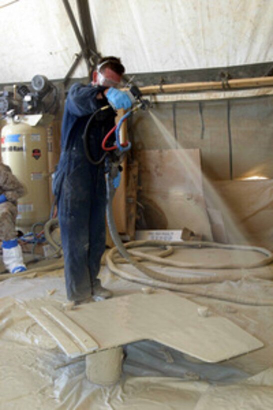 A U.S. Marine sprays an explosive resistant coating on an armored Humvee door at Camp Fallujah, Iraq, on July 24, 2004. The coating is helping to protect Marines from improvised explosive devices during Security and Stabilization Operations in the Al Anbar Province of Iraq. 