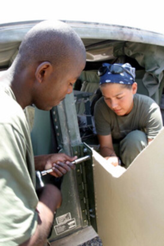 U.S. Marine Sgt. Wayne Campbell and Lance Cpl. Tiffaney Pilataxi attach an armored door treated with an explosive resistant coating to a Humvee at Camp Fallujah, Iraq, on July 24, 2004. The coating is helping to protect Marines from improvised explosive devices during Security and Stabilization Operations in the Al Anbar Province of Iraq. 