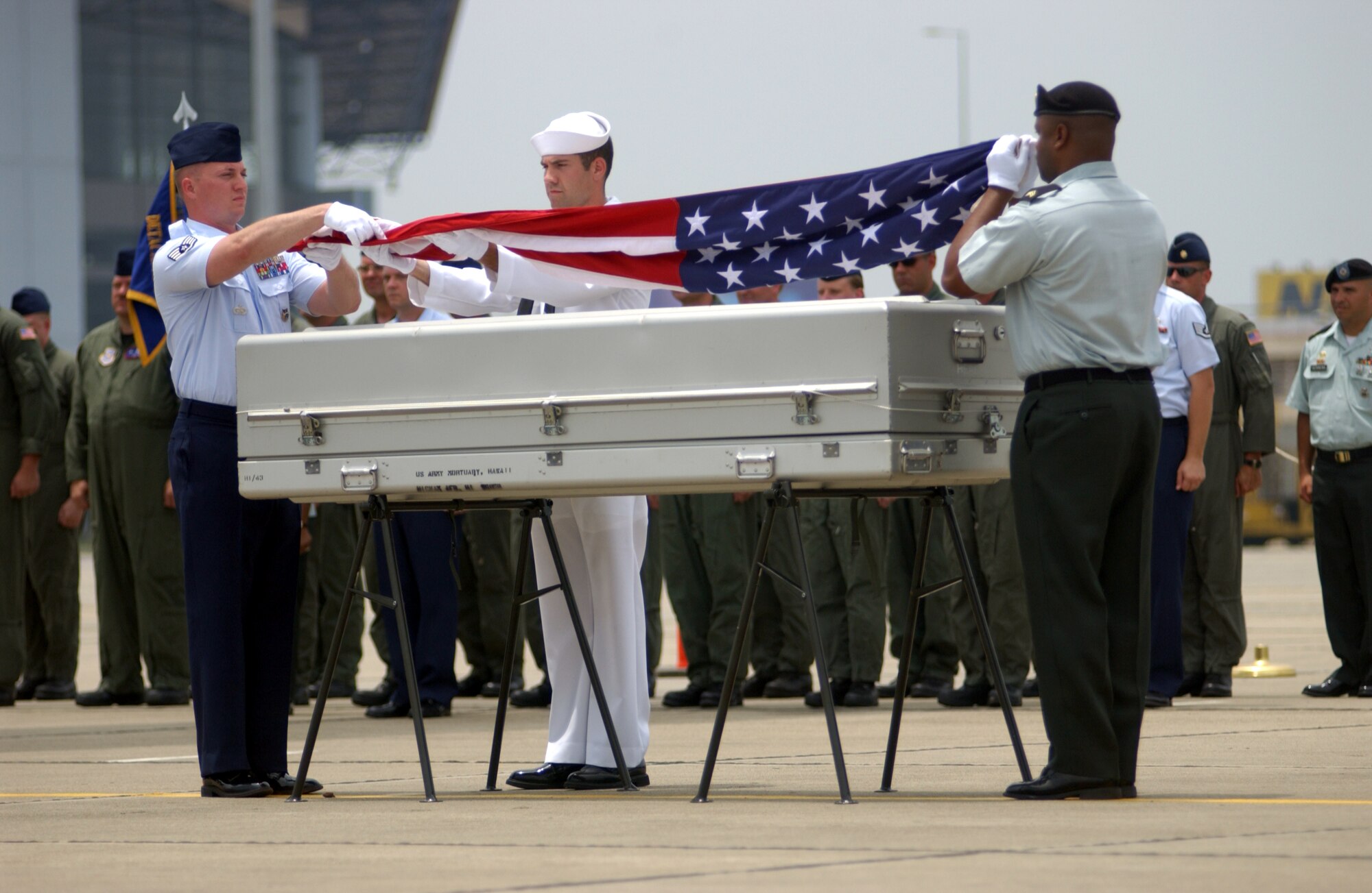 ANDERSEN AIR FORCE BASE, Guam -- Honor Guard members from the Joint POW/MIA Accounting Command drape an American flag over the remains of one of two servicemembers repatriated from Hanoi, Vietnam, on May 28.  Airmen of the 445th Airlift Wing and Maj. Gen. Ed Mechenbier, the last Airman still serving who was a prisoner of war in Vietnam, flew the Hanoi Taxi to bring their fallen comrades home.  The Hanoi Taxi became the first C-141 Startlifter to repatriate American POWs from Vietnam on Feb. 12, 1973.  (U.S. Air Force photo by Master Sgt. Ken Wright) 