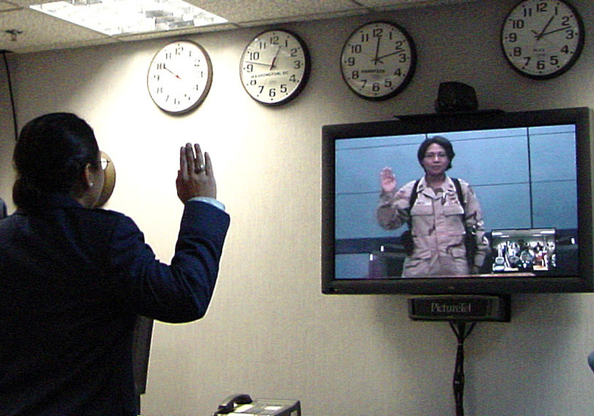 ROYAL AIR FORCE MILDENHALL, England -- First Lt. Joy Param, an intelligence officer with the 3rd Air Force (left), is promoted to captain by her sister, Army Capt. Jennifer Finch.  Captain Finch administered the oath of office to her sister via video teleconference from Iraq.  Captain Finch is the 502nd Military Intelligence commander.  (U.S. Air Force photo by Capt. Heather Healy)