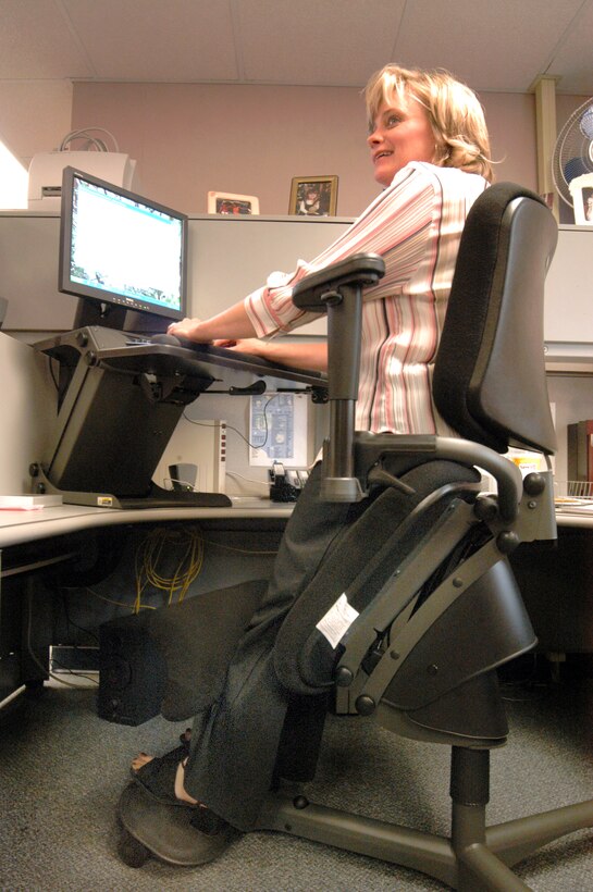 ROBINS AIR FORCE BASE, Ga. -- Melanie McDonald, a speech writer with the commander's action group here, uses a specially designed hydraulic chair and desk elevation system to help alleviate her back pain.  (U.S. Air Force photo by Sue Sapp)