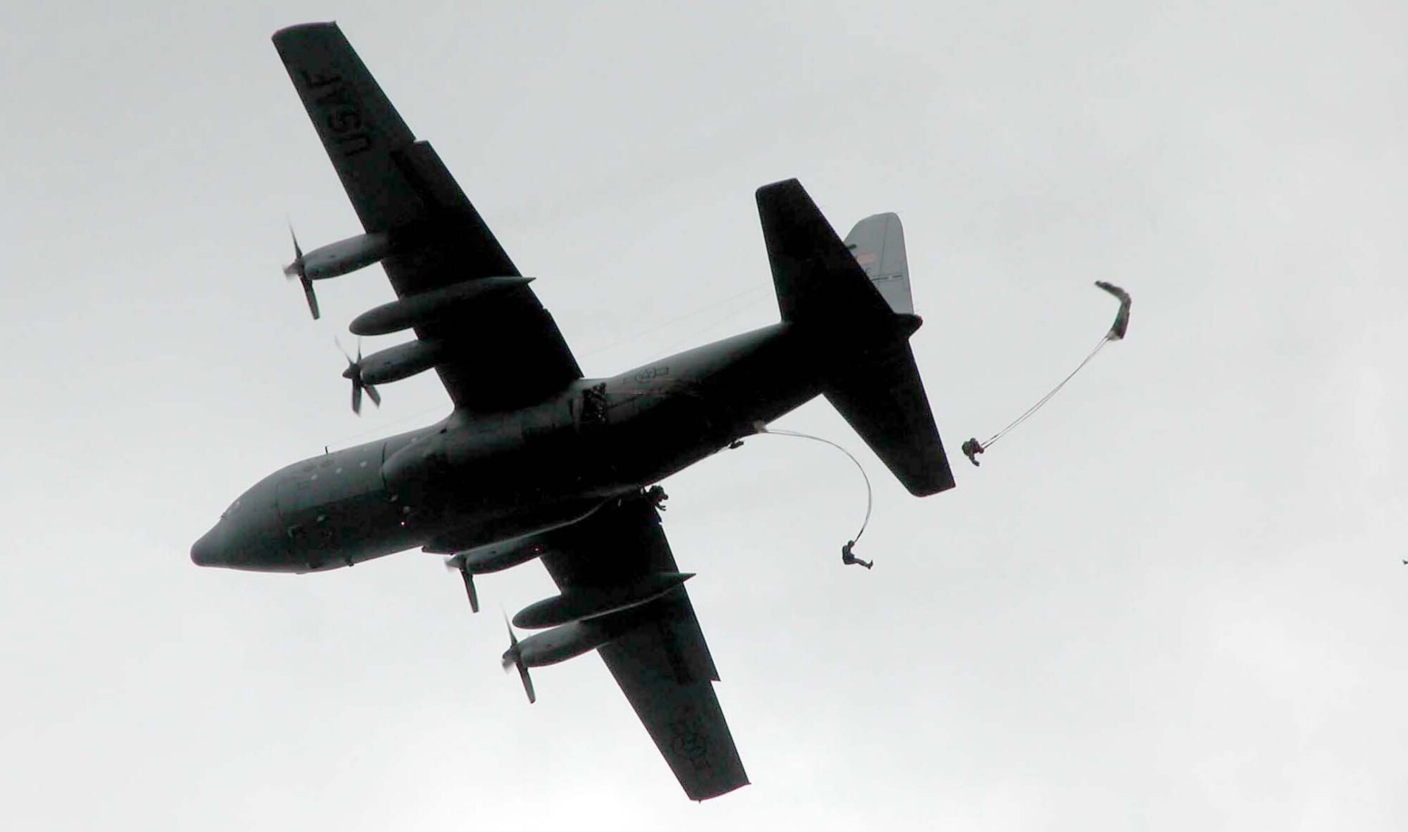 SAINTE-MERE-EGLISE, France -- Soldiers jump from a C-130 Hercules near here June 5 during a tribute to airborne Soldiers who died in the liberation of France in 1944.  Equipment and conditions in the 2004 commemoration jump stand in stark contrast to that of 60 years ago.  (Department of Defense photo by Jim Garamone)