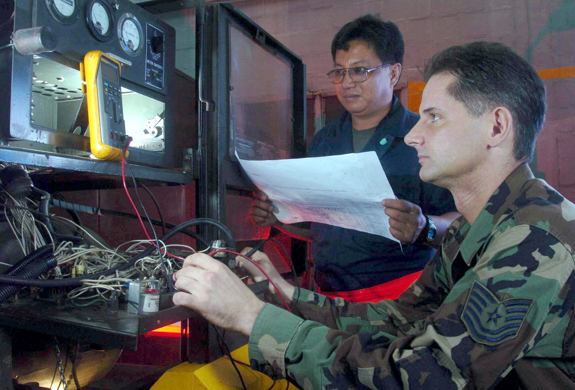 PAYA LABAR AIR BASE, Singapore -- Tech. Sgt. Darin Opalenik troubleshoots a generator with Wilfredo Ritumban, a civilian contractor, here.  Sergeant Opalenik is an aerospace ground equipment technician from the 497th Combat Training Squadron.  The squadron supports regular temporary-duty rotations of U.S. fighter aircraft.  (U.S. Air Force photo by Master Sgt. Val Gempis)