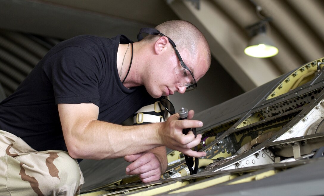SOUTHWEST ASIA -- Senior Airman James Flinchbaugh works on the safety wiring heat shield on an F-16 Fighting Falcon at a forward-deployed location.  He is assigned to the 379th Expeditionary Maintenance Squadron and is deployed from the Vermont Air National Guard's 158th Fighter Wing.  (U.S. Air Force photo by Tech. Sgt. Demetrius Lester)
