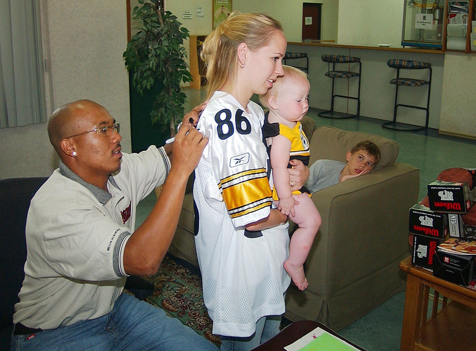 INCIRLIK AIR BASE, Turkey -- Hines Ward, Pittsburgh Steeler wide receiver, signs Susan Perkin's jersey while she holds her 14-month-old daughter, Mattie, here June 17.  Mr. Ward stopped here as part of a U.S. Air Forces in Europe tour.  (U.S. Air Force photo by Senior Airman James Seymore)