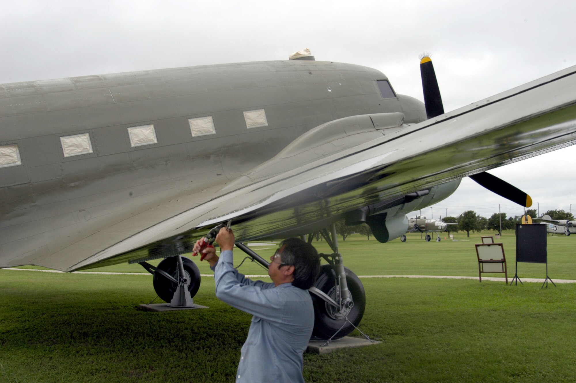 LACKLAND AIR FORCE BASE, Texas -- Miguel Basaldua removes buckled and corroded sheet metal on the wing of a C-47 Skytrain here.  He is a contracted sheet-metal specialist who restores planes around the base.  (U.S. Air Force photo by James Coburn)