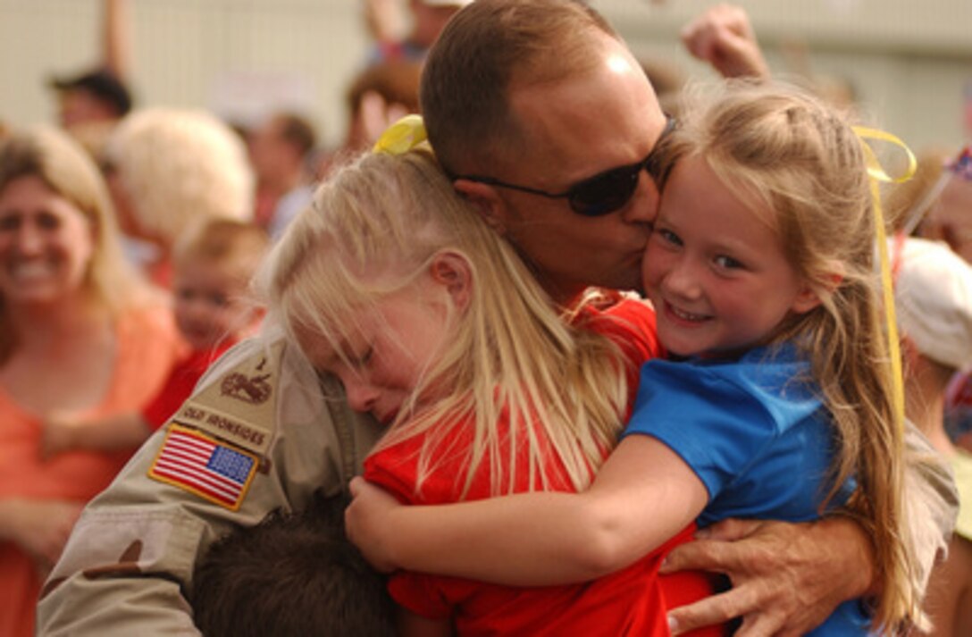 A soldier from the 210th Military Police Company, North Carolina Army National Guard, hugs his children as he returns to Asheville Regional Airport, N.C., on June 10, 2004, after being deployed for over 15 months in Iraq. 