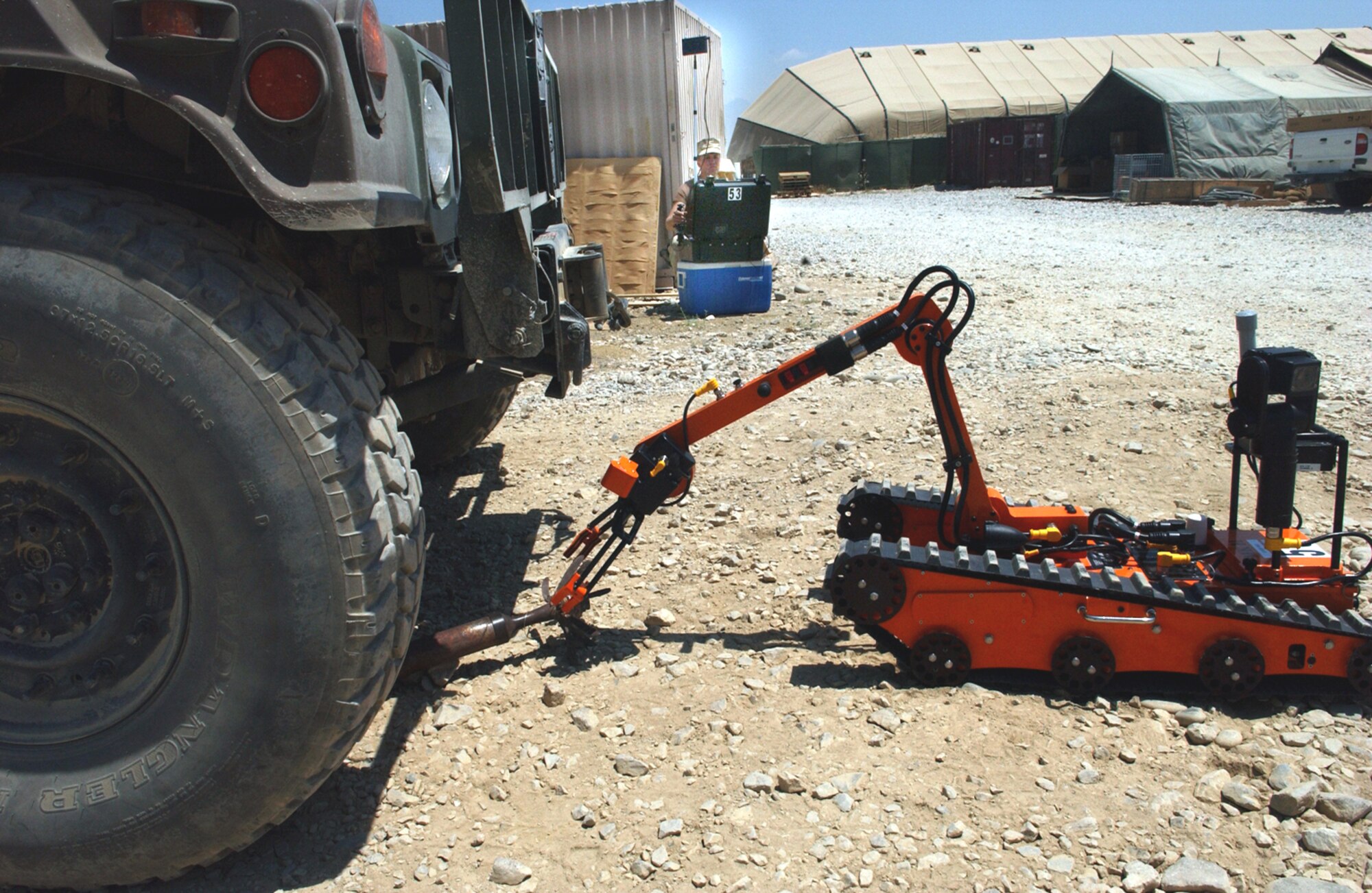 BAGRAM AIR BASE, Afghanistan -- "Lucky Day," a robot used by explosive ordnance disposal technicians, picks up a rocket motor from underneath a Humvee during training.  Robots are often used to retrieve ordnance from difficult to reach or dangerous locations.  Airman 1st Class Nicholas (background) controls the robot by remote control.  Airman Nicholas is assigned to the 455th Expeditionary Civil Engineer Flight here.  (U.S. Air Force photo by Master Sgt. Andrew Gates)