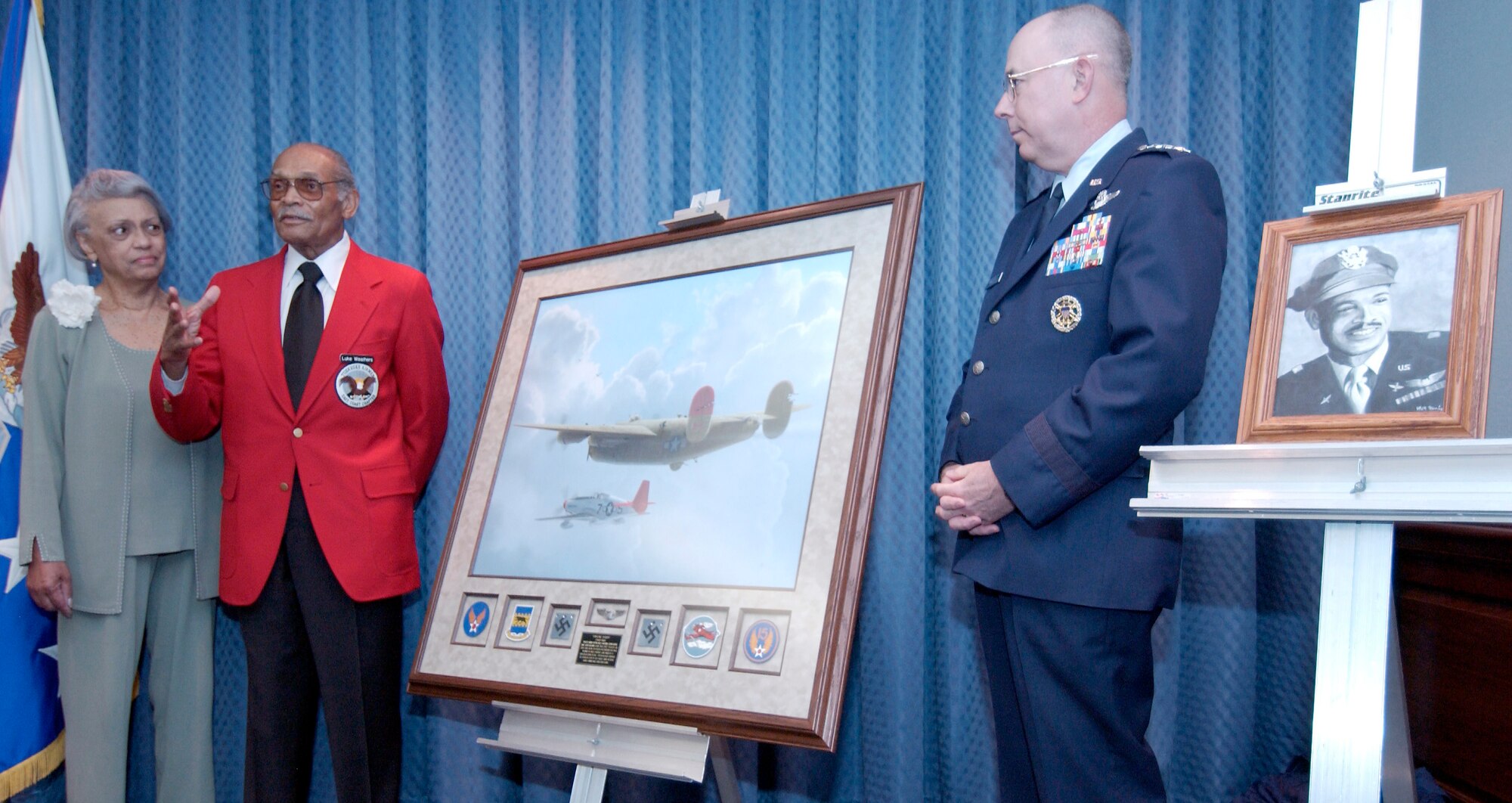 WASHINGTON -- Air Force Vice Chief of Staff Gen. T. Michael Moseley (right) and Jacqueline Weathers (left) look on as her husband, retired Lt. Col. Luke Weathers, describes the action depicted in a painting honoring the famed 332nd Fighter Group of Tuskegee Airmen.  Colonel Weathers and General Moseley unveiled during a ceremony in the Pentagon on June 24.  (U.S. Air Force photo by Master Sgt. Jim Varhegyi)