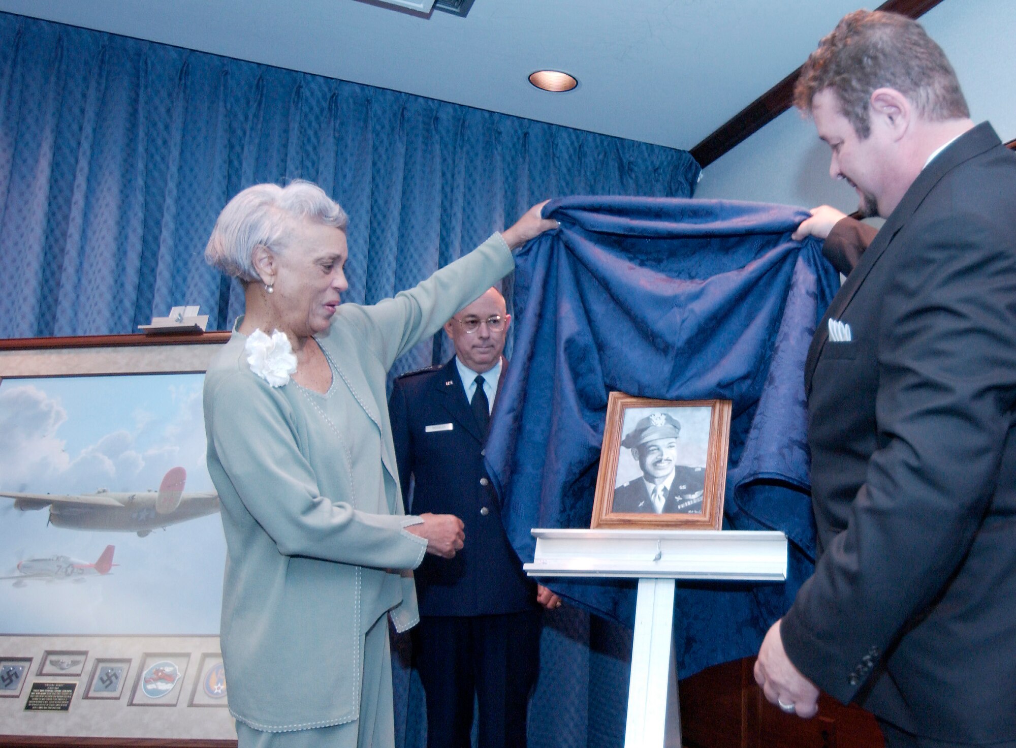 WASHINGTON -- Jacqueline Weathers (left) and artist Mickey Harris unveil a portrait of her husband, retired Lt. Col. Luke Weathers, which was painted by Mr. Harris' son, Matthew.  Air Force Vice Chief of Staff Gen. T. Michael Moseley looks on in the background.  Earlier, General Moseley and Colonel Weathers unveiled a painting honoring the famed 332nd Fighter Group of Tuskegee Airmen during a ceremony in the Pentagon on June 24.  (U.S. Air Force photo by Master Sgt. Jim Varhegyi)