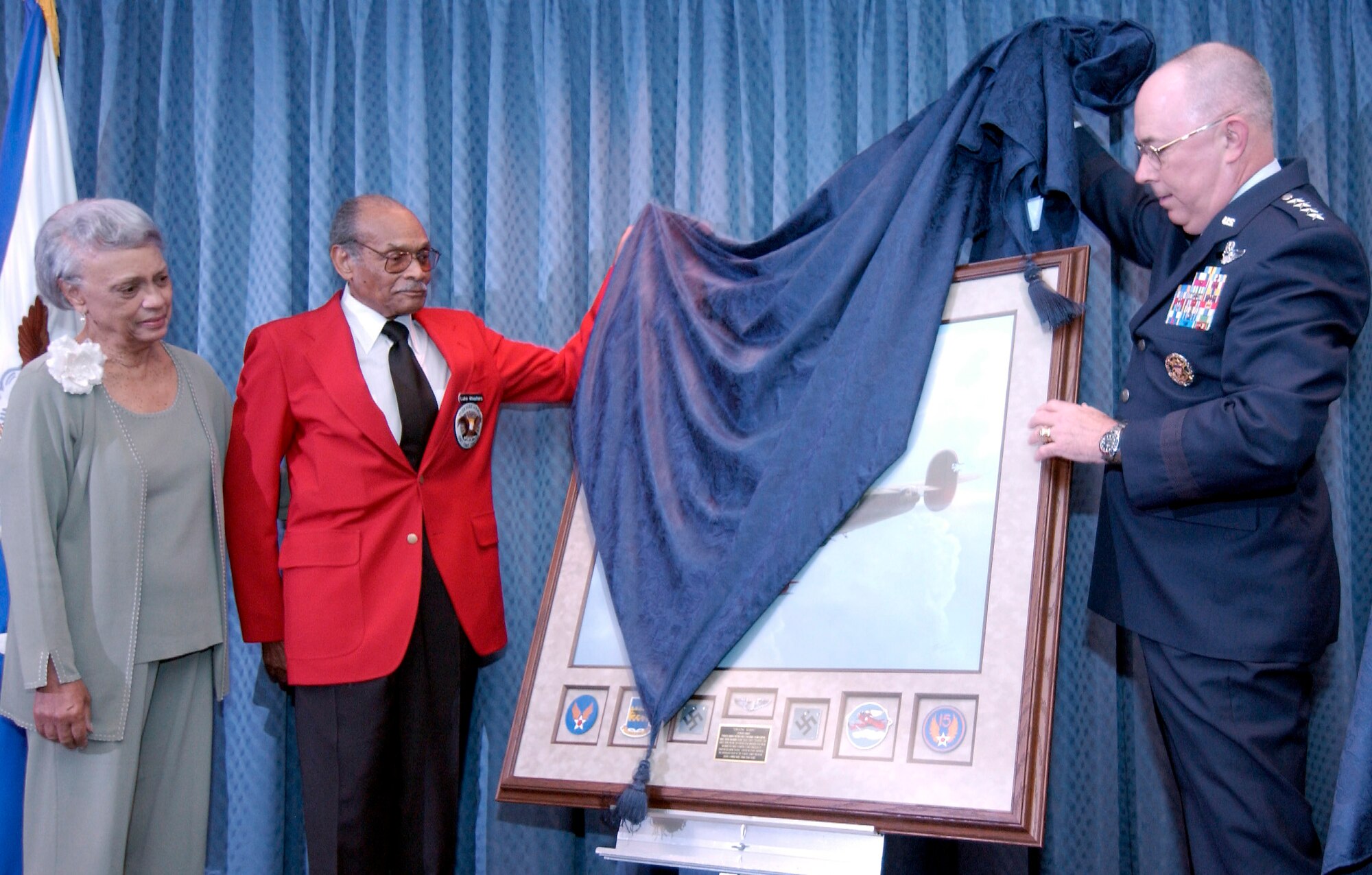 WASHINGTON -- Jacqueline Weathers (left) looks on as her husband, retired Lt. Col. Luke Weathers (center), and Air Force Vice Chief of Staff Gen. T. Michael Moseley unveil a painting during a ceremony June 24 in the Pentagon.  The painting pays tribute to the unblemished record of the famed 332nd Fighter Group of Tuskegee Airman.  (U.S. Air Force photo by Master Sgt. Jim Varhegyi)