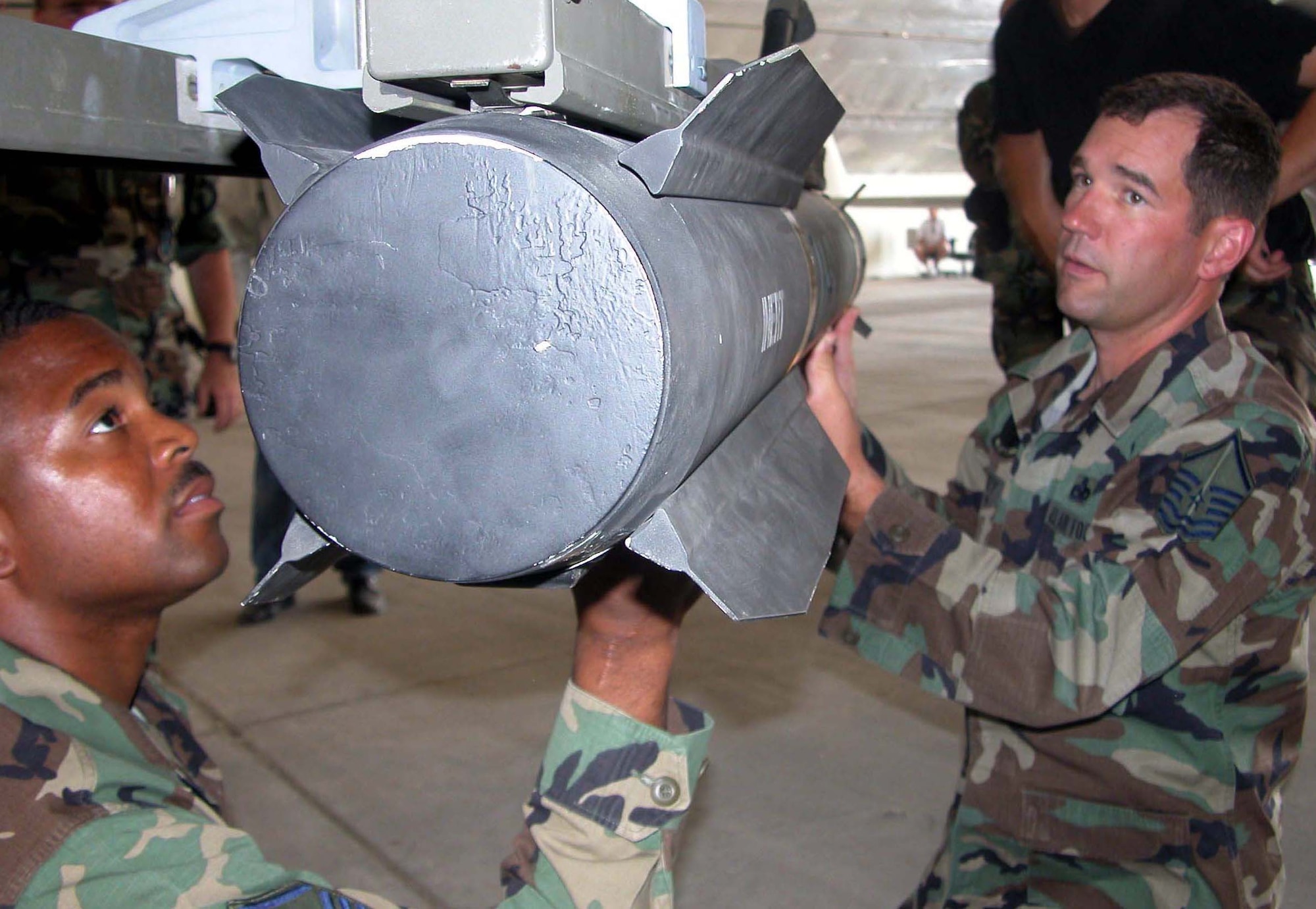 INDIAN SPRINGS AIR FORCE AUXILIARY FIELD, Nev. -- Master Sgts. Michael Brooks (left) and Lloyd Canty load an inert Hellfire missile onto an MQ-1 Predator here June 17 as part of a test of the Joint Multiplatform Weapons Carriage System.  The Airmen are assigned to the 757th Aircraft Maintenance Squadron.  (U.S. Air Force photo by Staff Sgt. Chris Stagner)