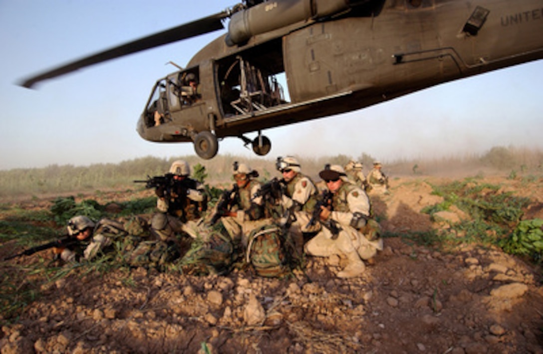 Members of Bravo Section, 2nd Brigade Recon Troop, brace themselves in a security posture after being infiltrated by a UH-60A Black Hawk helicopter during a Quick Response Force Weapons Interdiction mission in Iraq on June 19, 2004. The Quick Response Force responds to immediate action situations directed by the Tactical Operations Center commander. 