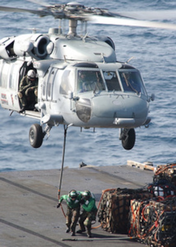 Flight deck crewmen on the USNS Supply (T-AOE 6) run from under a MH-60S Seahawk helicopter after hooking up a load of supplies during an underway replenishment in the Persian Gulf on June 23, 2004. The Seahawk is transporting materiel to the aircraft carrier USS George Washington (CVN 73). 