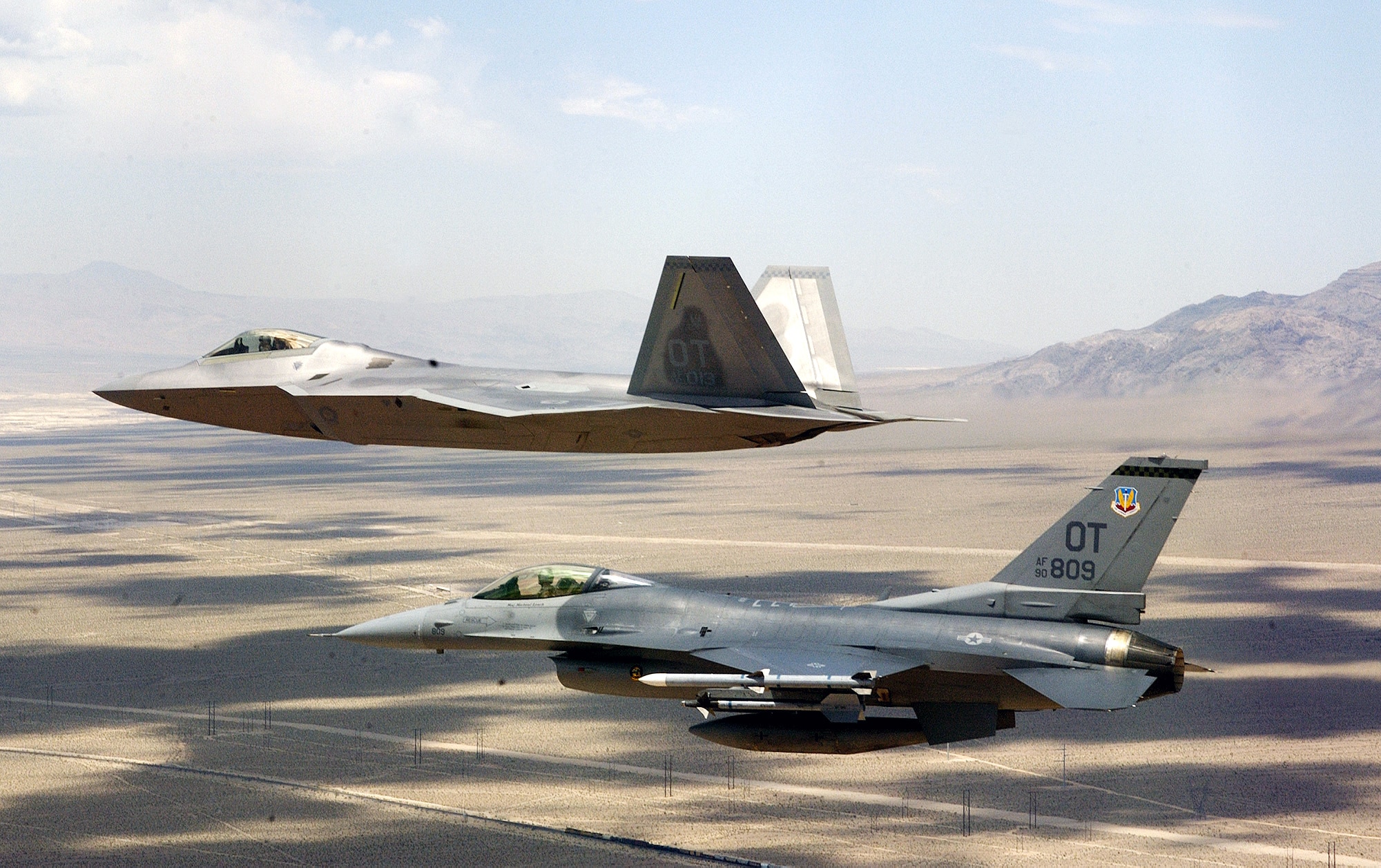 NELLIS AIR FORCE BASE, Nev. -- An F/A-22 Raptor flown by Maj. David Thole flies fingertip formation on a training mission June 23 alongside an F-16 Fighting Falcon flown by Maj. Alex Grynkewich.  Major Thole is assigned to the 422nd Test and Evaluation Squadron, and Major Grynkewich is from the 53rd Test and Evaluation Group.  (U.S. Air Force photo by Tech. Sgt. Kevin J. Gruenwald)