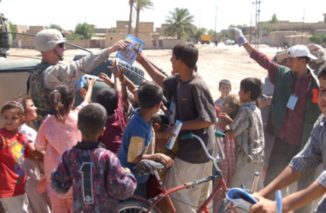 Army soldiers with Air Defense Artillery, 1st Battalion, 2nd Armored Cavalry Regiment, pass out educational coloring and activity books to Iraqi children in the suburbs of Al Kut, Iraq, on June 6, 2004. 