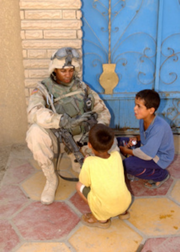 A U.S. Army soldier spends some spare time talking with two local boys in Sadr City, Iraq, on June 19, 2004. 