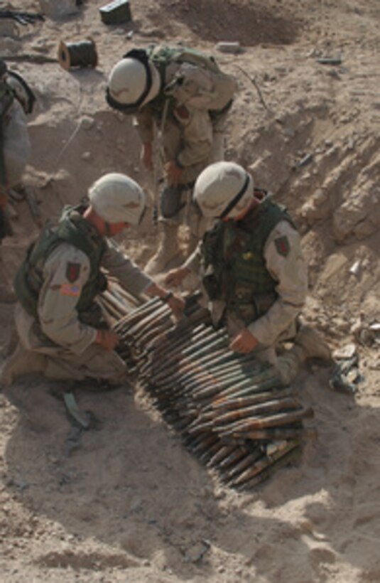 Soldiers from Alpha Company, 9th Engineer Battalion, place C-4 explosives onto 37mm anti-aircraft rounds to be destroyed near the city of Bayji, Iraq, on June 20, 2004. Soldiers are conducting unexploded ordnance clearance to prevent injuries or deaths to the Coalition Forces and civilian personnel and prevent their use as improvised explosive devices. 