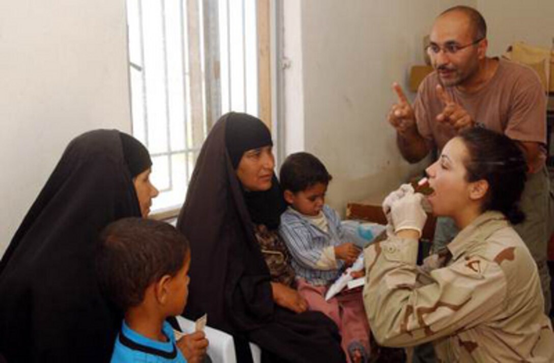 Army dental technician Spc. Elizabeth Jarry shows local Iraqi mothers and their sons the proper way to floss their teeth while an interpreter translates, on June 22, 2004. Jarry a dental technician with headquarters and Service Company (HSC) 118th, LSA Anaconda is part of a medical Civil Assistance Program in a Iraqi village near LSA Anaconda. 